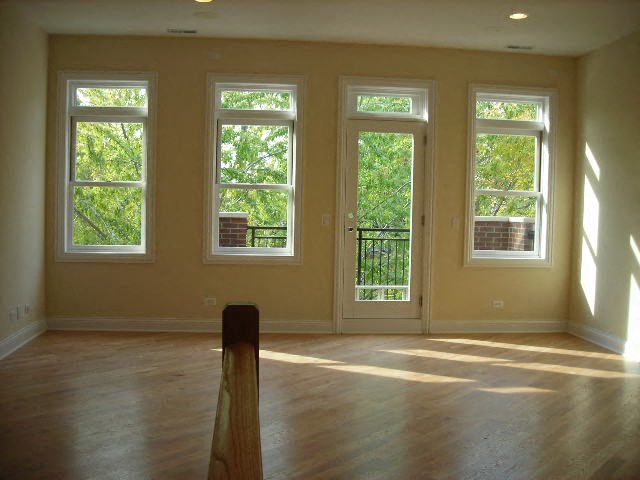 an empty living room with four windows and a wooden floor