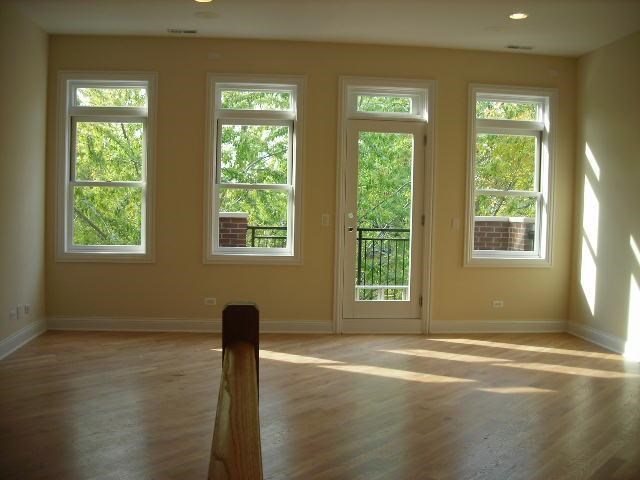 an empty living room with four windows and a wooden floor