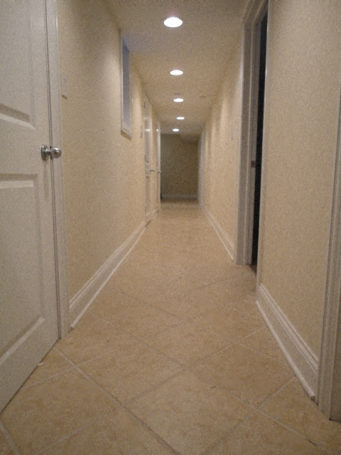 a long hallway with white walls and white doors and a tile floor