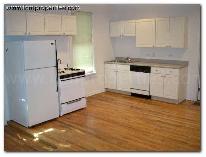 a kitchen with white appliances and a wooden floor