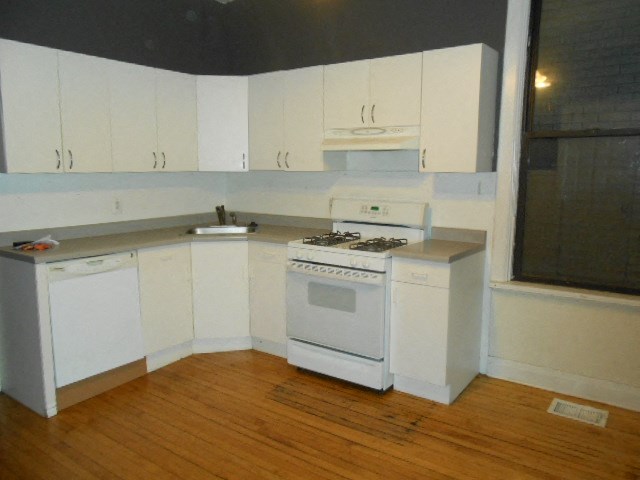 an empty kitchen with white cabinets and a stove