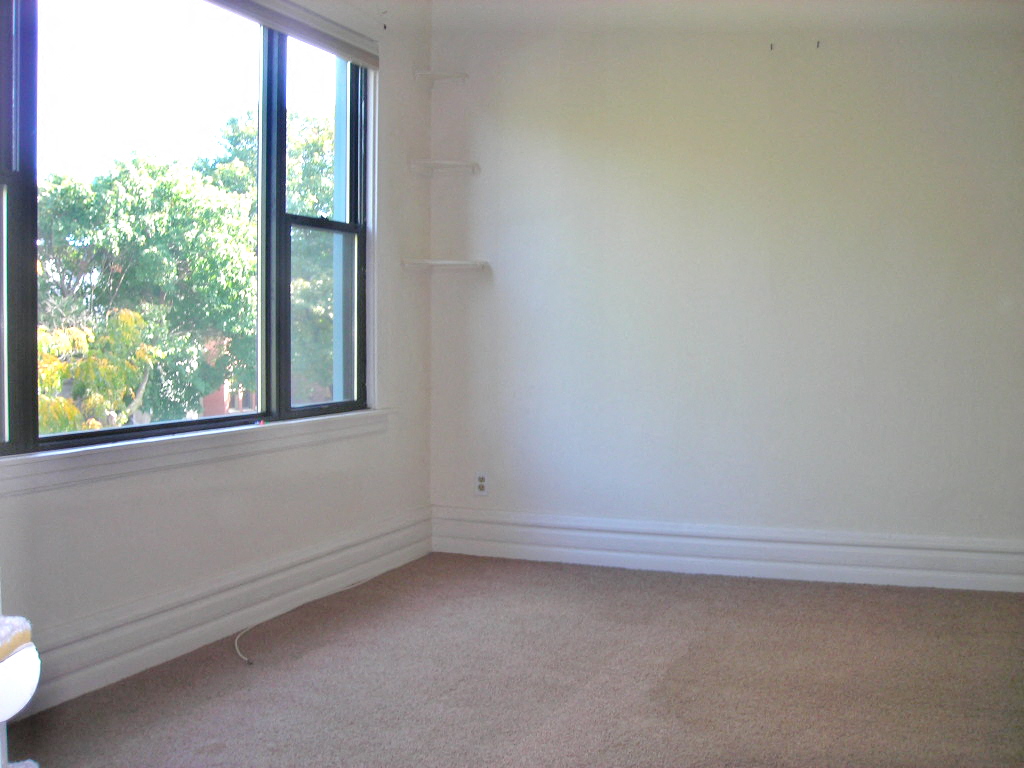a bedroom with a large window and a carpeted floor