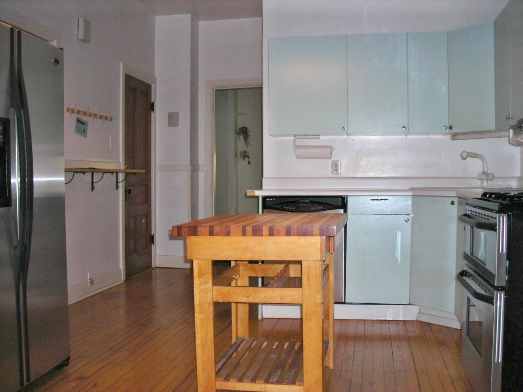 an empty kitchen with a wooden table in the middle