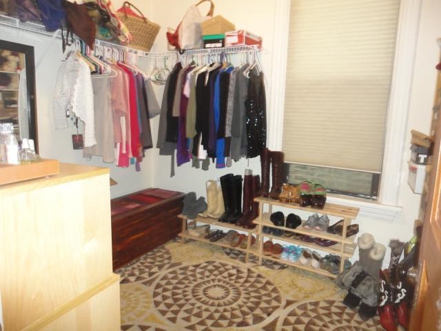 a bedroom with a closet with clothes hanging on a rack