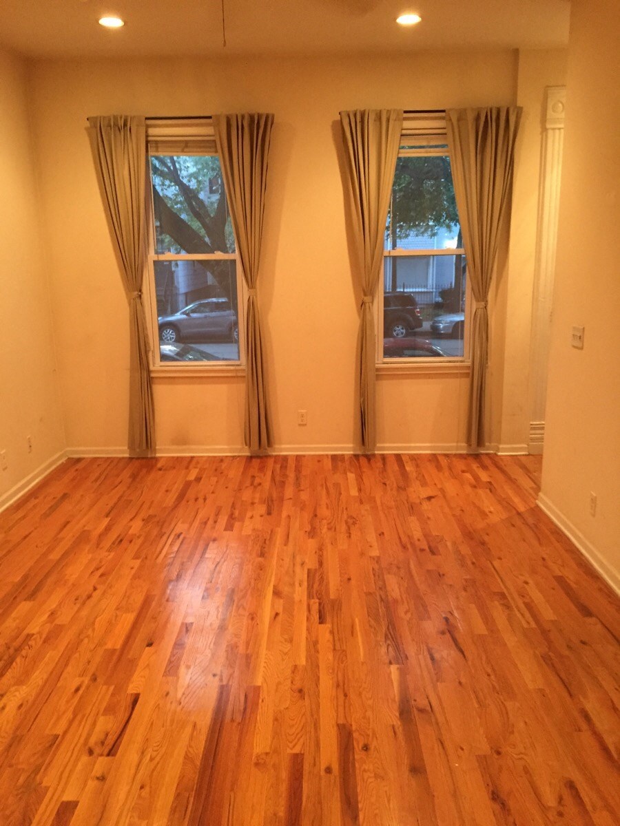 a living room with a hard wood floor and two windows