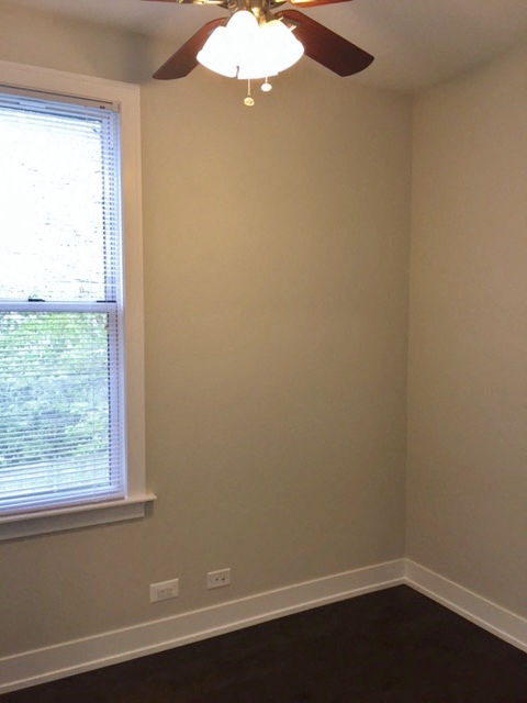 an empty room with a ceiling fan and a window