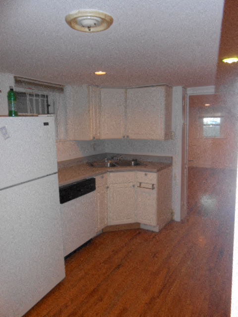 an empty kitchen with white cabinets and a refrigerator