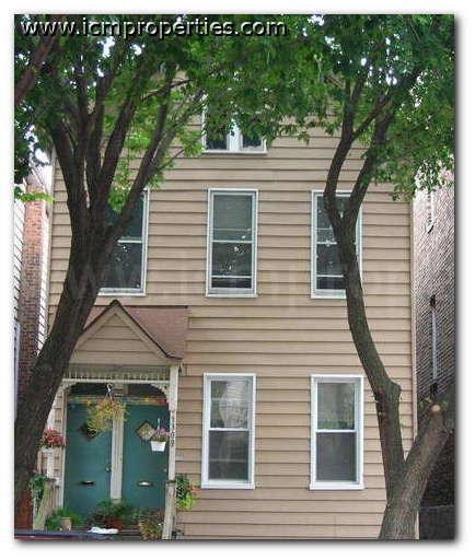 a tan house with a green door and a tree