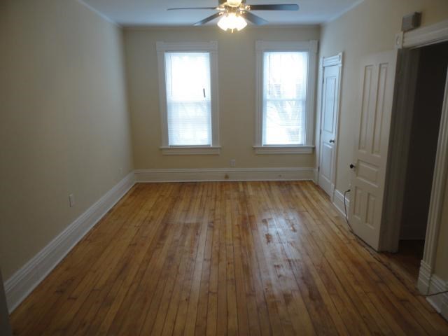 an empty living room with wood floors and a ceiling fan