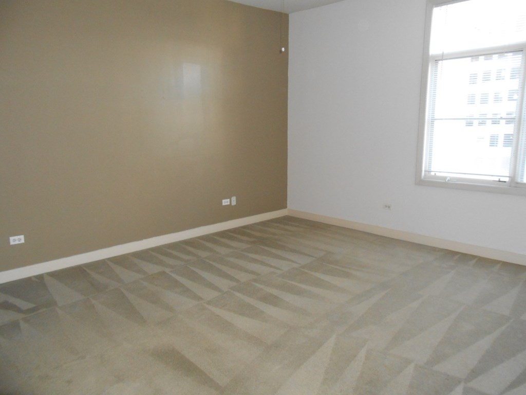 an empty room with wooden floors and two windows