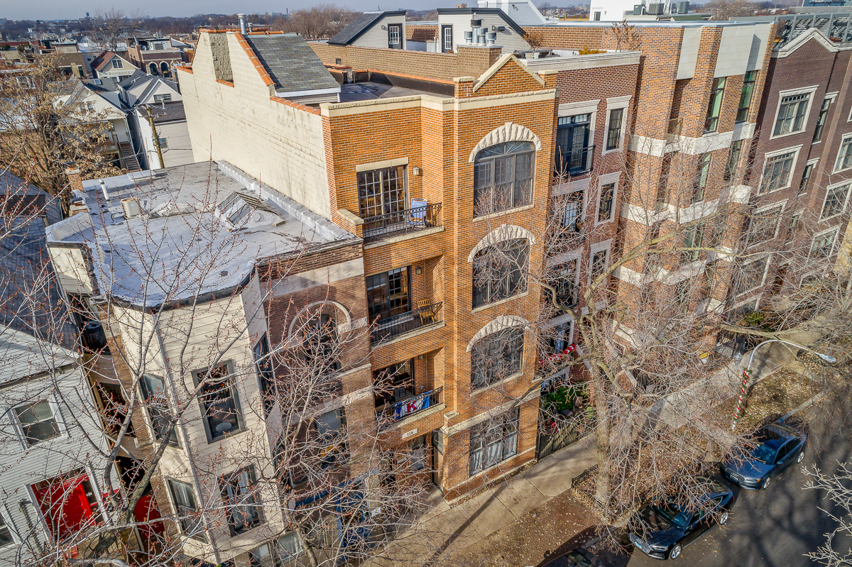an aerial view of a brick building with cars parked outside