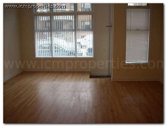an empty living room with wood floors and a window