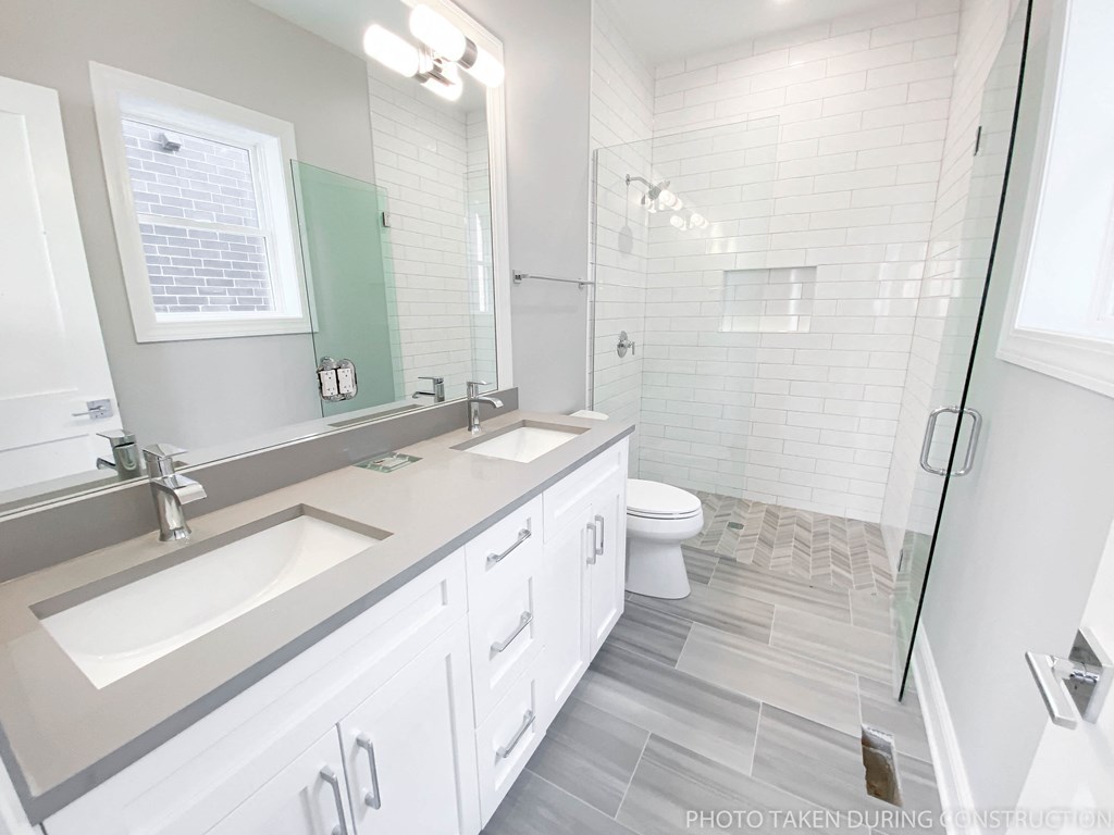 a bathroom with two sinks and a shower and a toilet