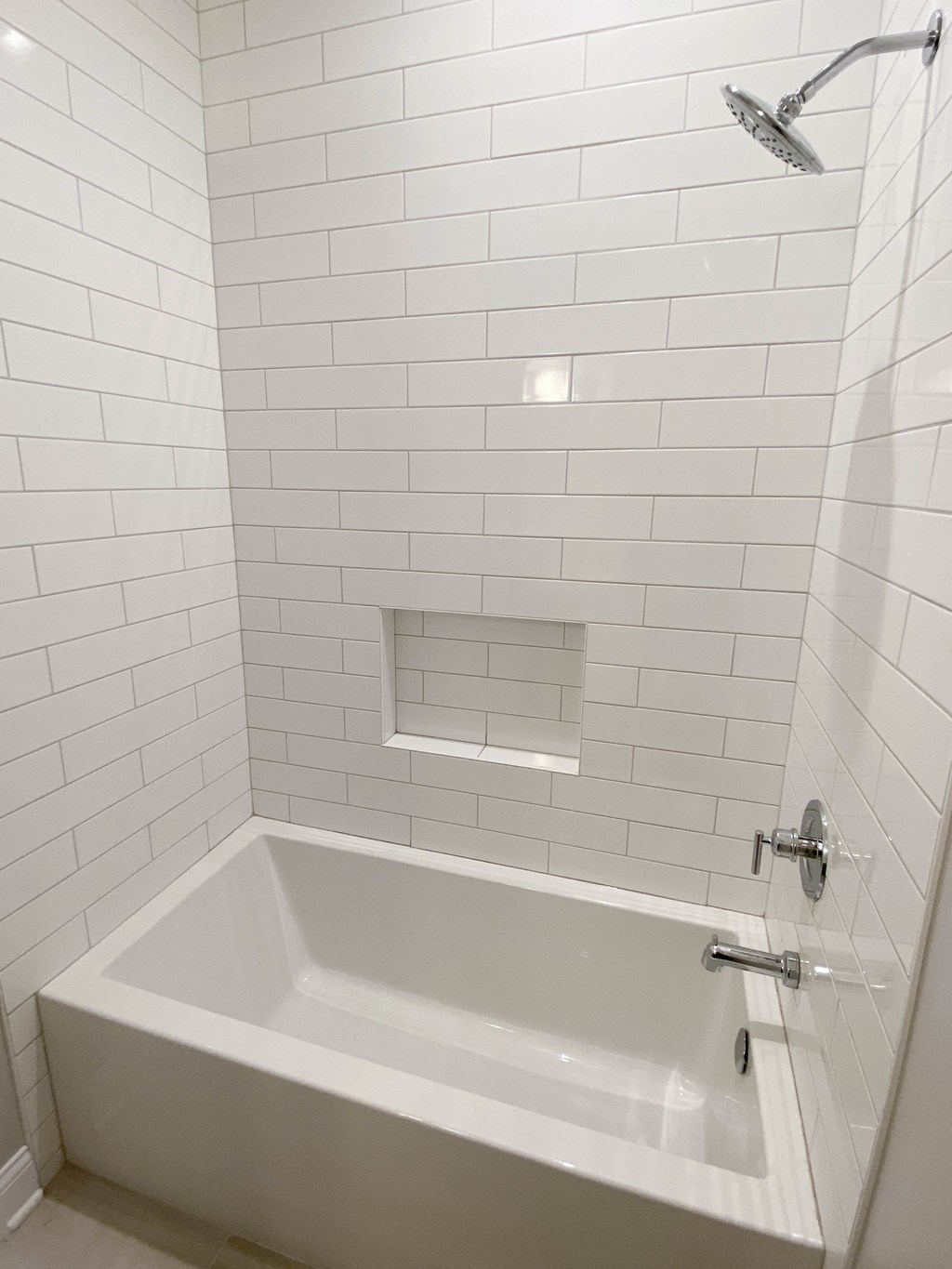 a white tiled bathroom with a tub and a shower