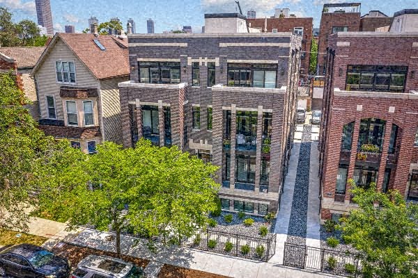 an aerial view of a brick building with trees and cars