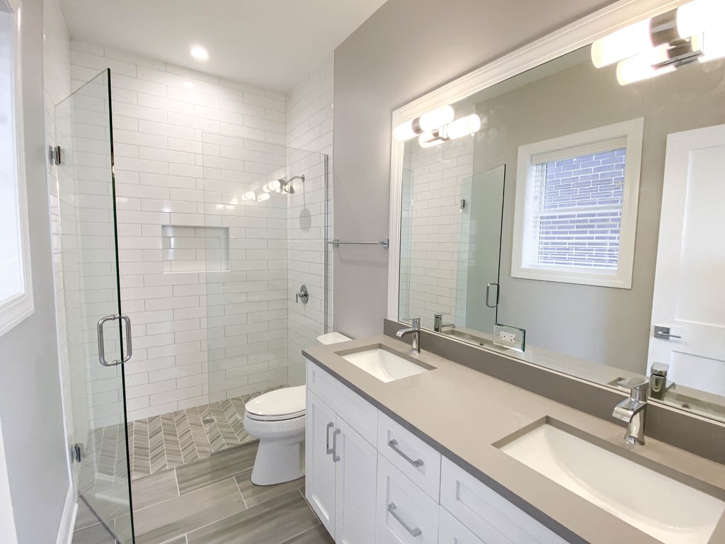 a bathroom with two sinks and a shower and a toilet