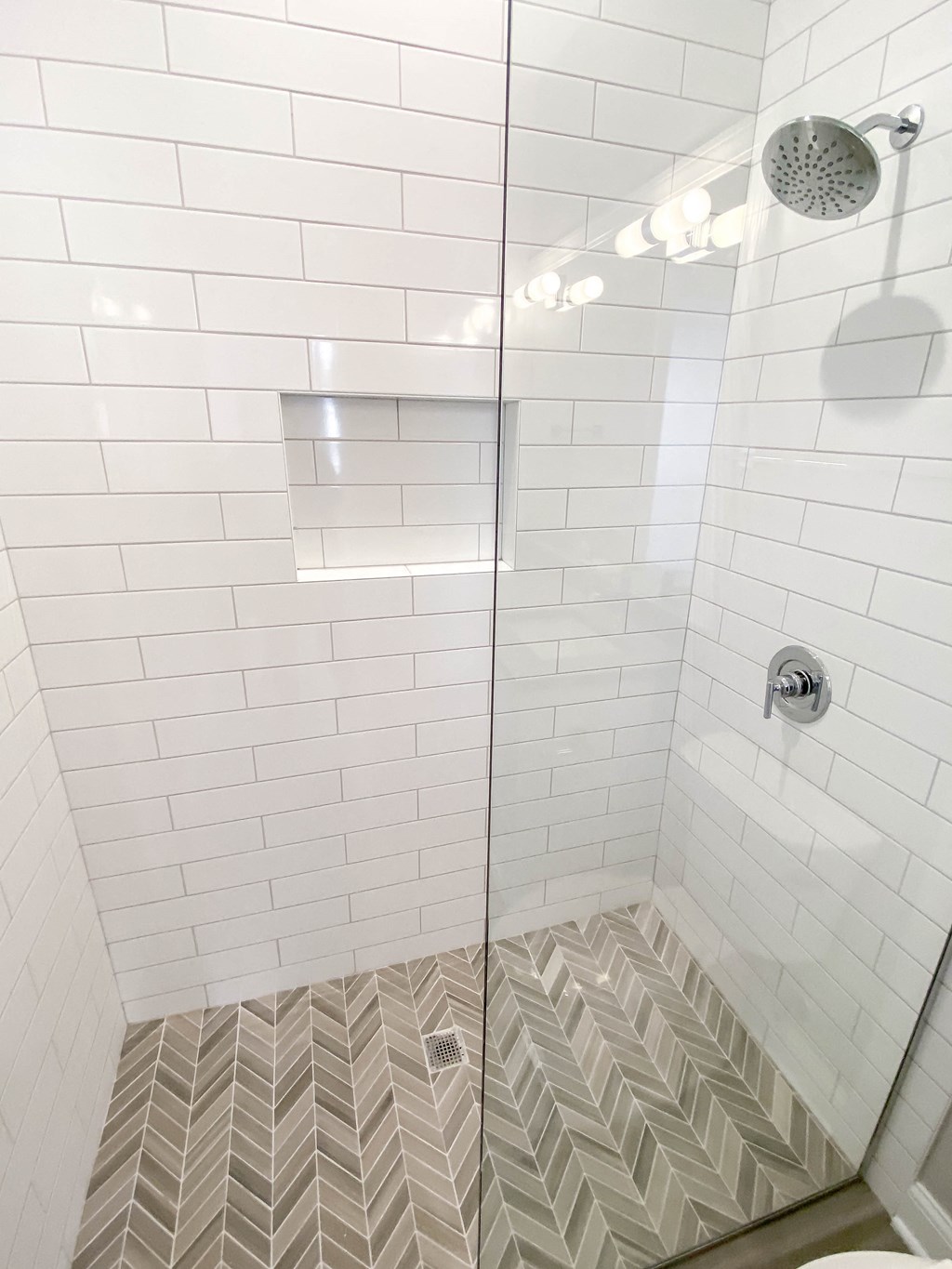 a small shower with white tile and a glass door