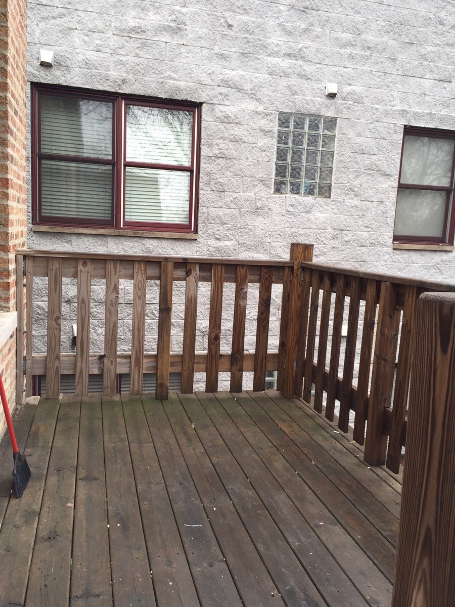 a backyard deck with a white wall and a wooden railing