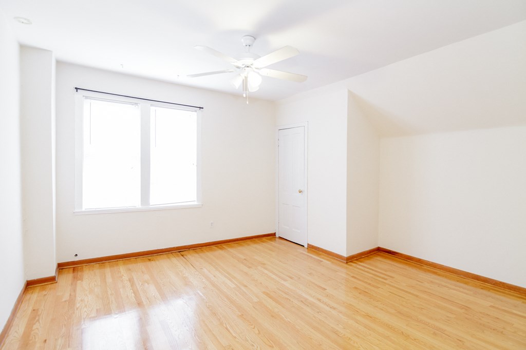 an empty room with wood floors and a ceiling fan