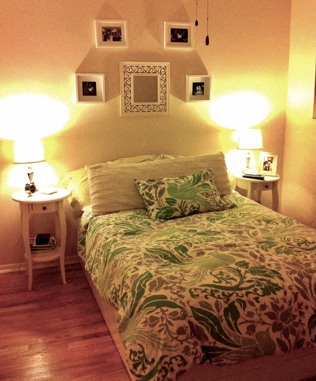 a bedroom with a bed and lamps and pictures on the wall