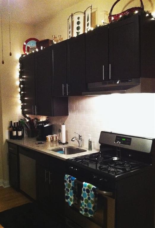 a kitchen with black cabinets and a stove and a sink