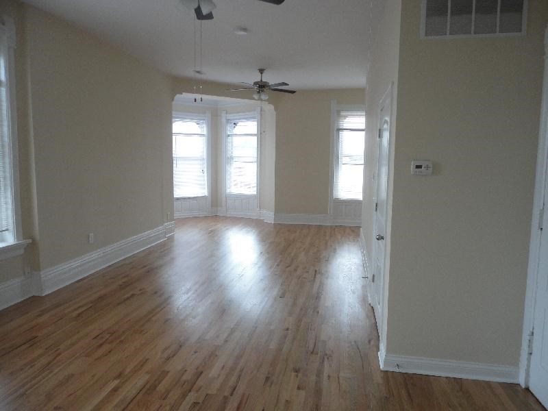 an empty living room with wood floors and a ceiling fan
