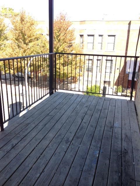a balcony with a wooden floor and a black railing