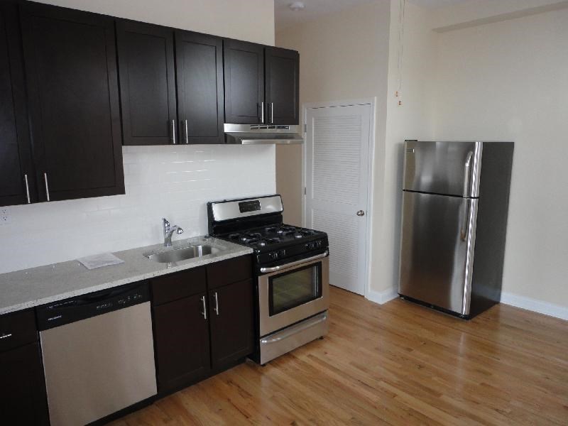 a kitchen with black cabinets and a stainless steel refrigerator