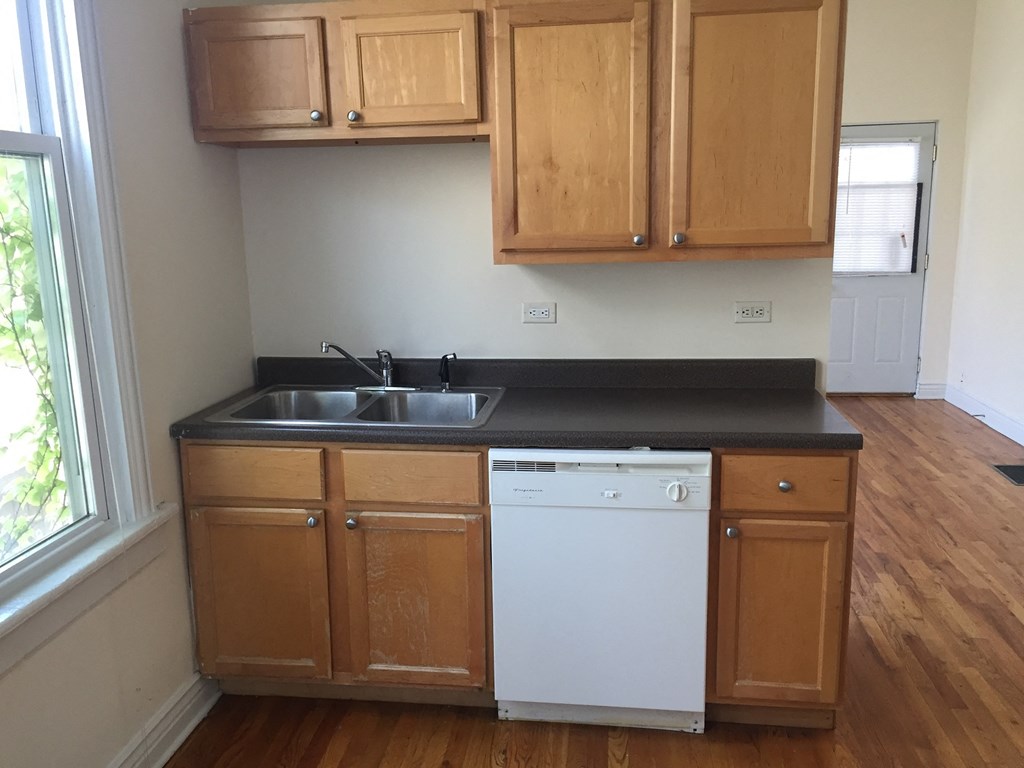 an empty kitchen with wooden cabinets and a white dishwasher