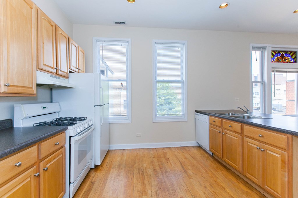 a kitchen with wood floors and white appliances and wooden cabinets