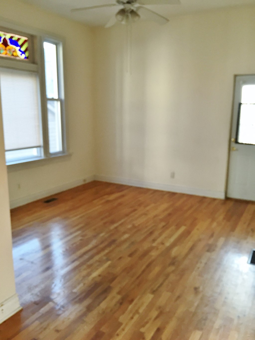 an empty living room with wooden floors and a window