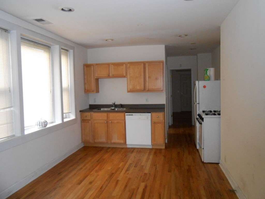 an empty kitchen with wooden floors and white appliances