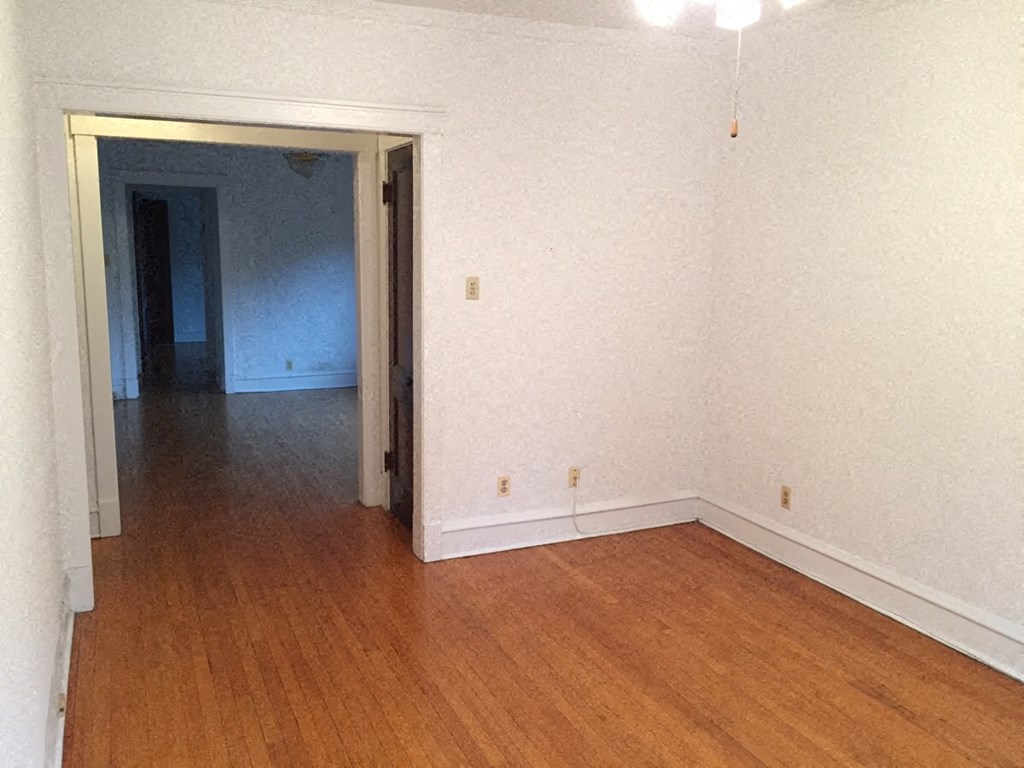 an empty living room with a wooden floor and white walls