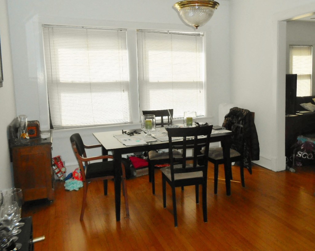 a dining room with a wooden floor and a table and chairs