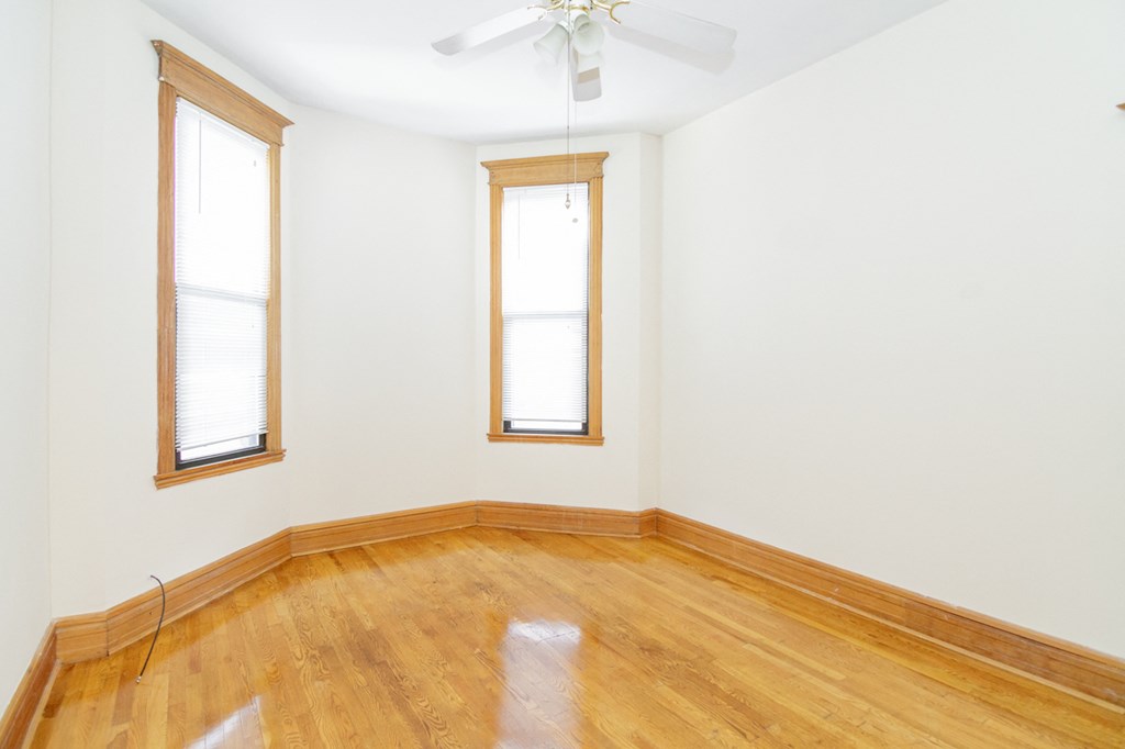 an empty room with wooden floors and two windows