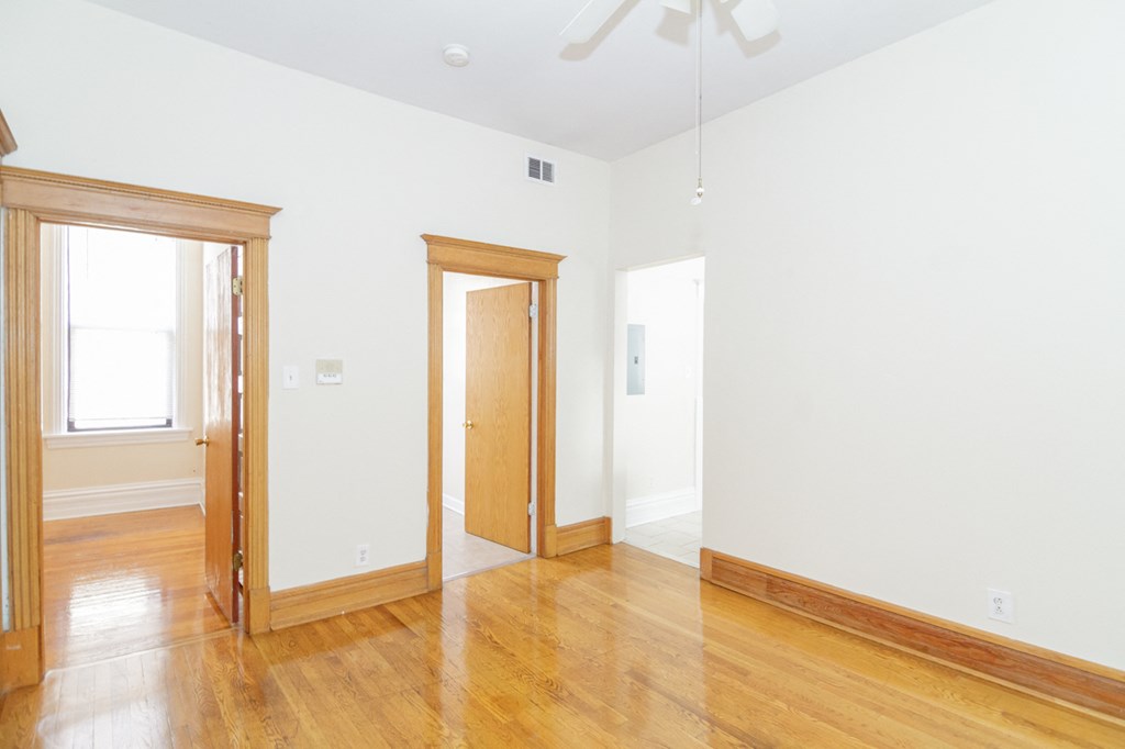 an empty living room with wood floors and white walls