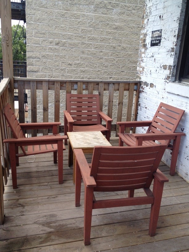 a group of wooden chairs sitting on a porch