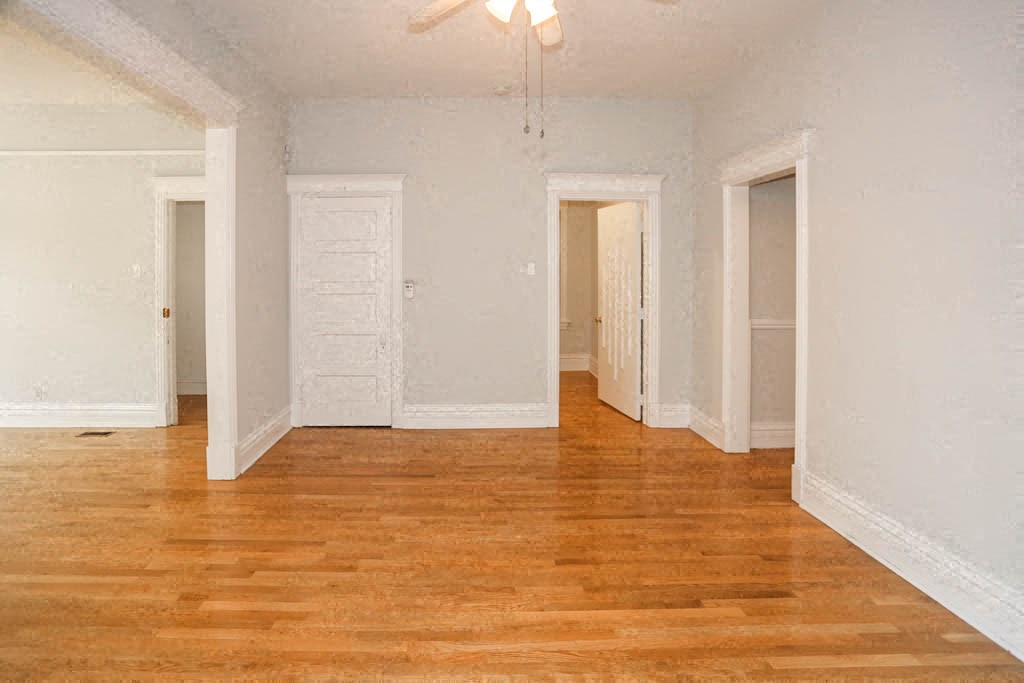 an empty living room with wood floors and white walls