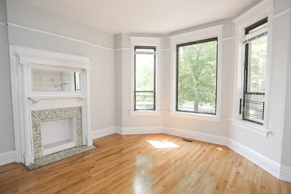 an empty living room with a fireplace and wood floors