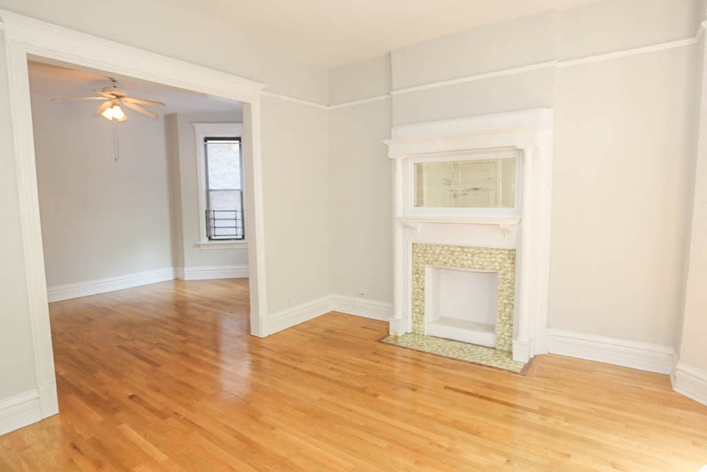 an empty living room with a fireplace and wooden floors