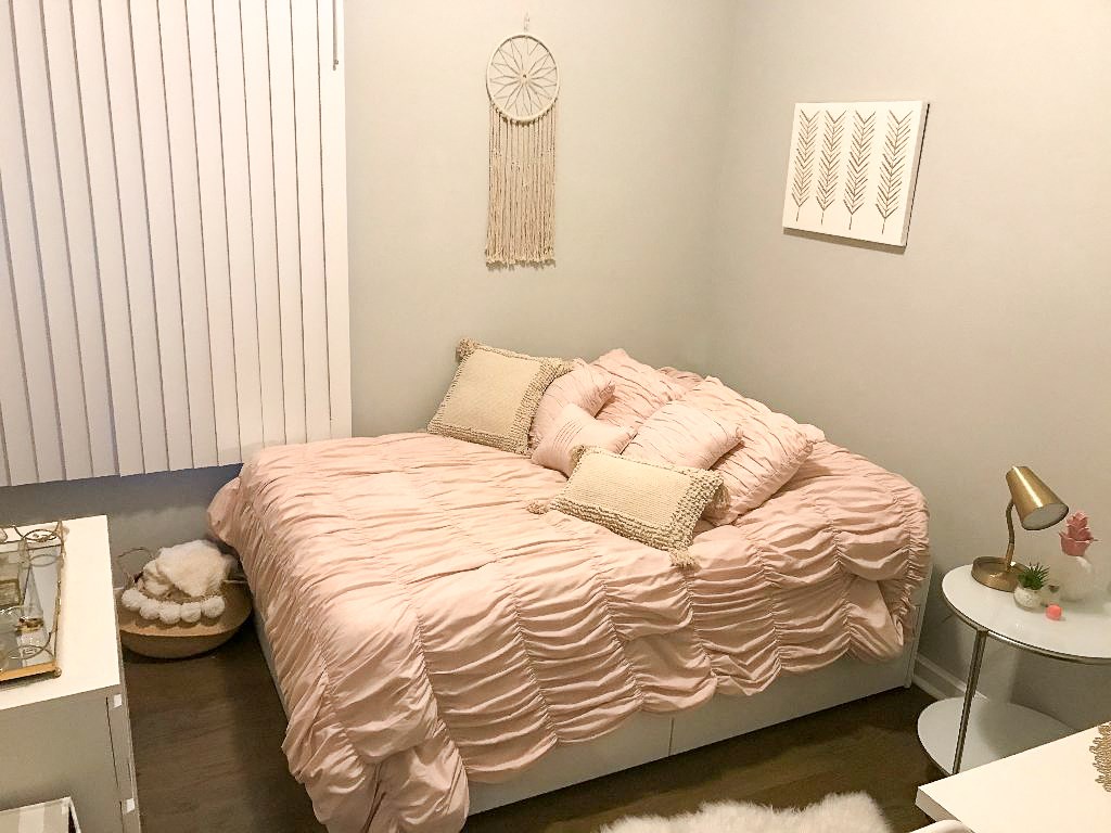 a bedroom with a bed with a pink comforter and pillows