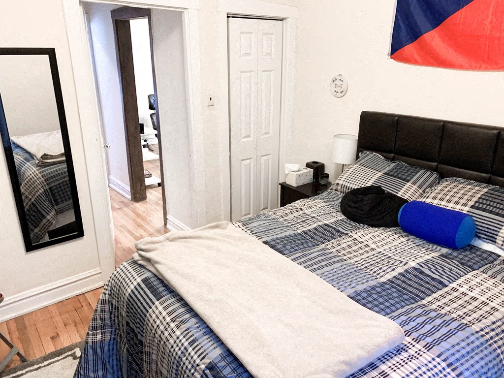 a bedroom with a bed with a blue and white comforter and a mirror