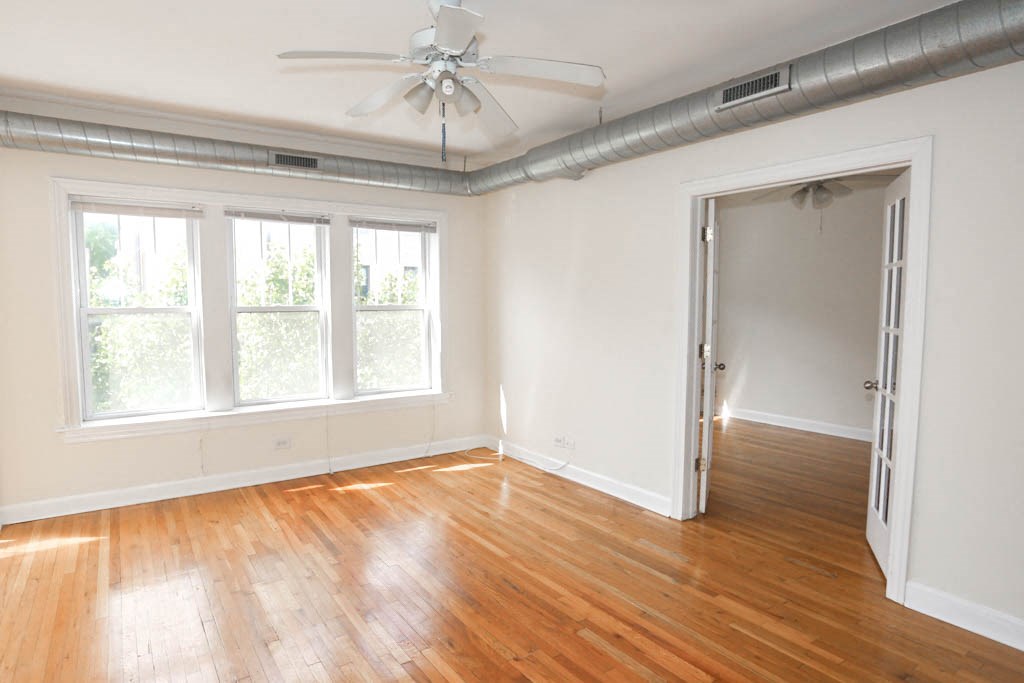 an empty living room with wood floors and a ceiling fan