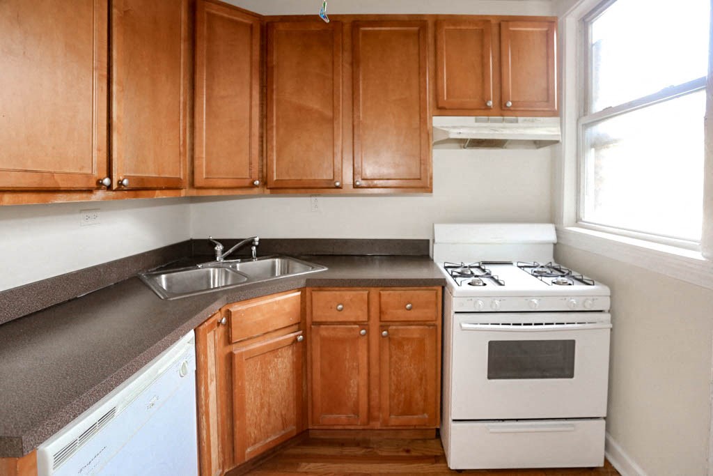 a kitchen with a stove and a sink and wooden cabinets