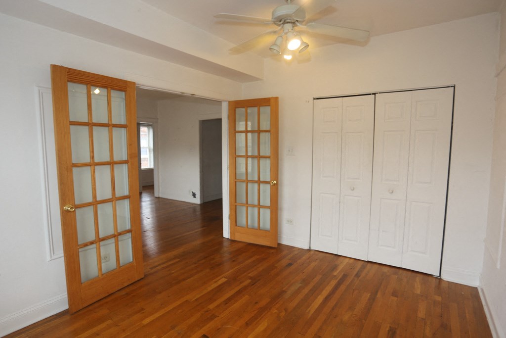 an empty living room with two doors and a ceiling fan
