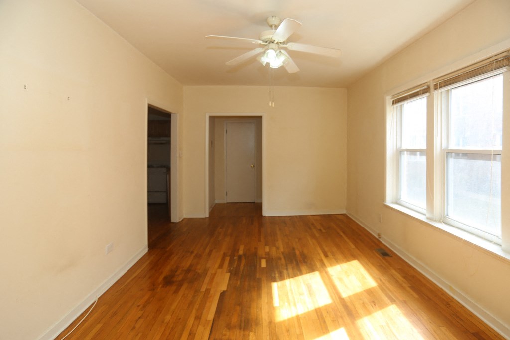 an empty living room with wood floors and a ceiling fan