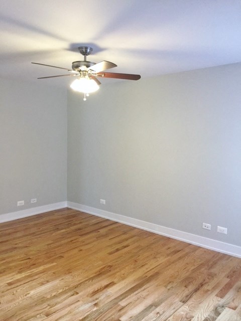 an empty room with a ceiling fan and wood floors
