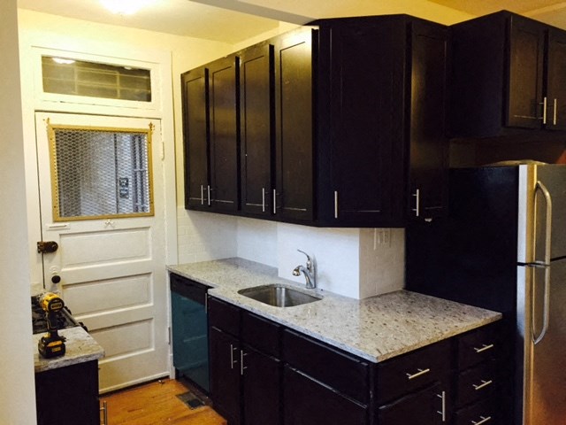 a kitchen with black cabinets and a sink and a refrigerator