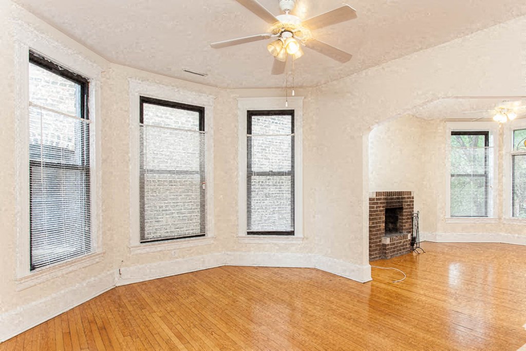 an empty living room with a fireplace and a ceiling fan