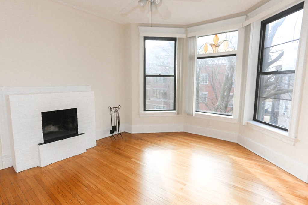an empty living room with a fireplace and a wooden floor